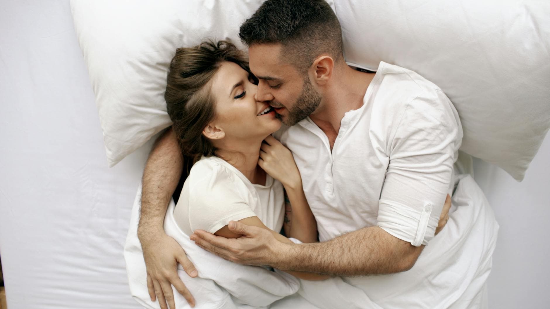 A loving couple embracing in bed, capturing intimacy and affection.