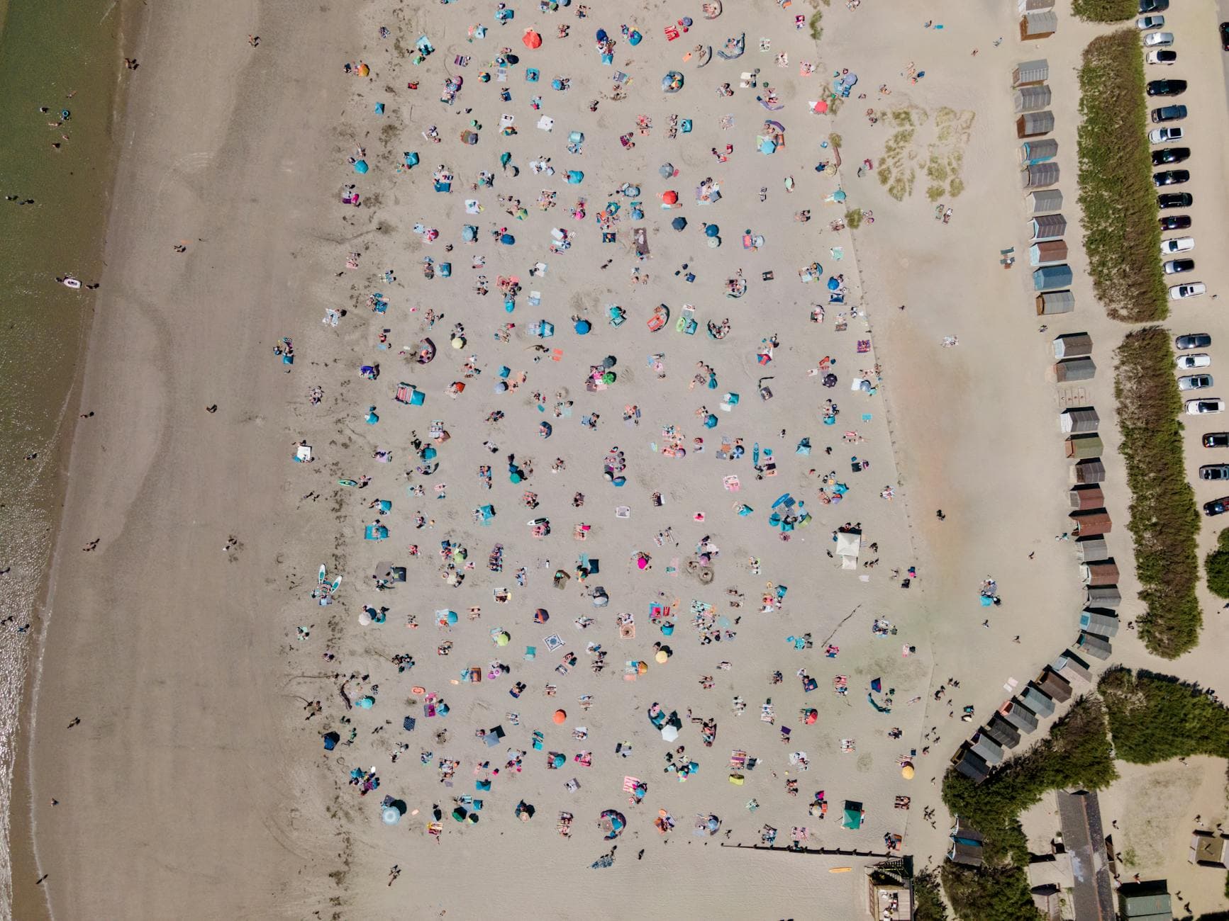 A bird's eye view of West Wittering beach in England, bustling with people on a sunny day.