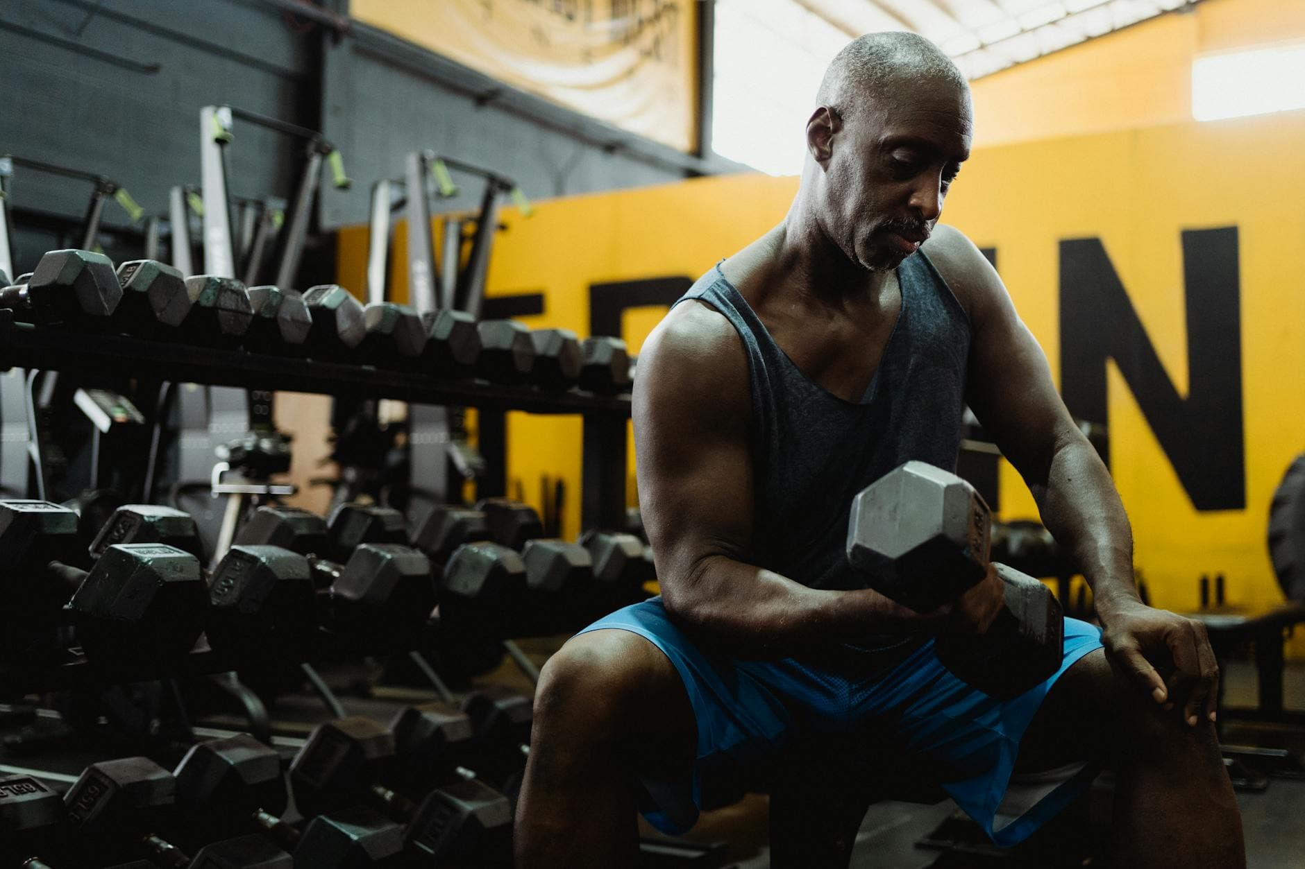 Focused man lifting weights in a gym, building strength and muscle.