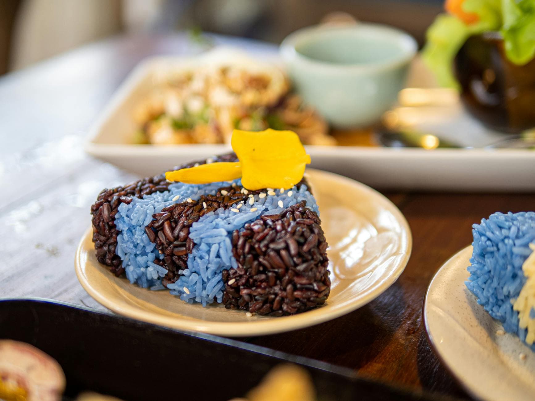 Close-up of vibrant blue and black sticky rice with mango on a plate, showcasing traditional Thai cuisine.