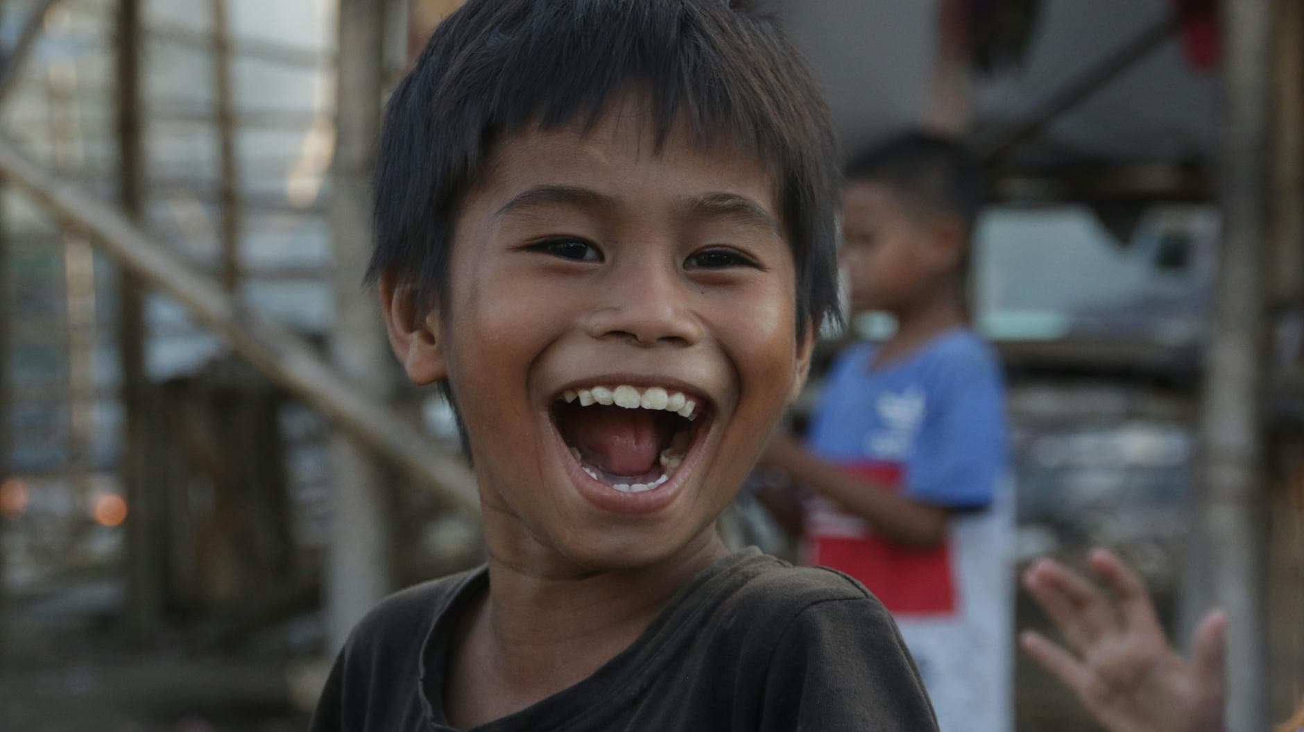 A cheerful Asian boy with a big smile outdoors, expressing happiness and joy.
