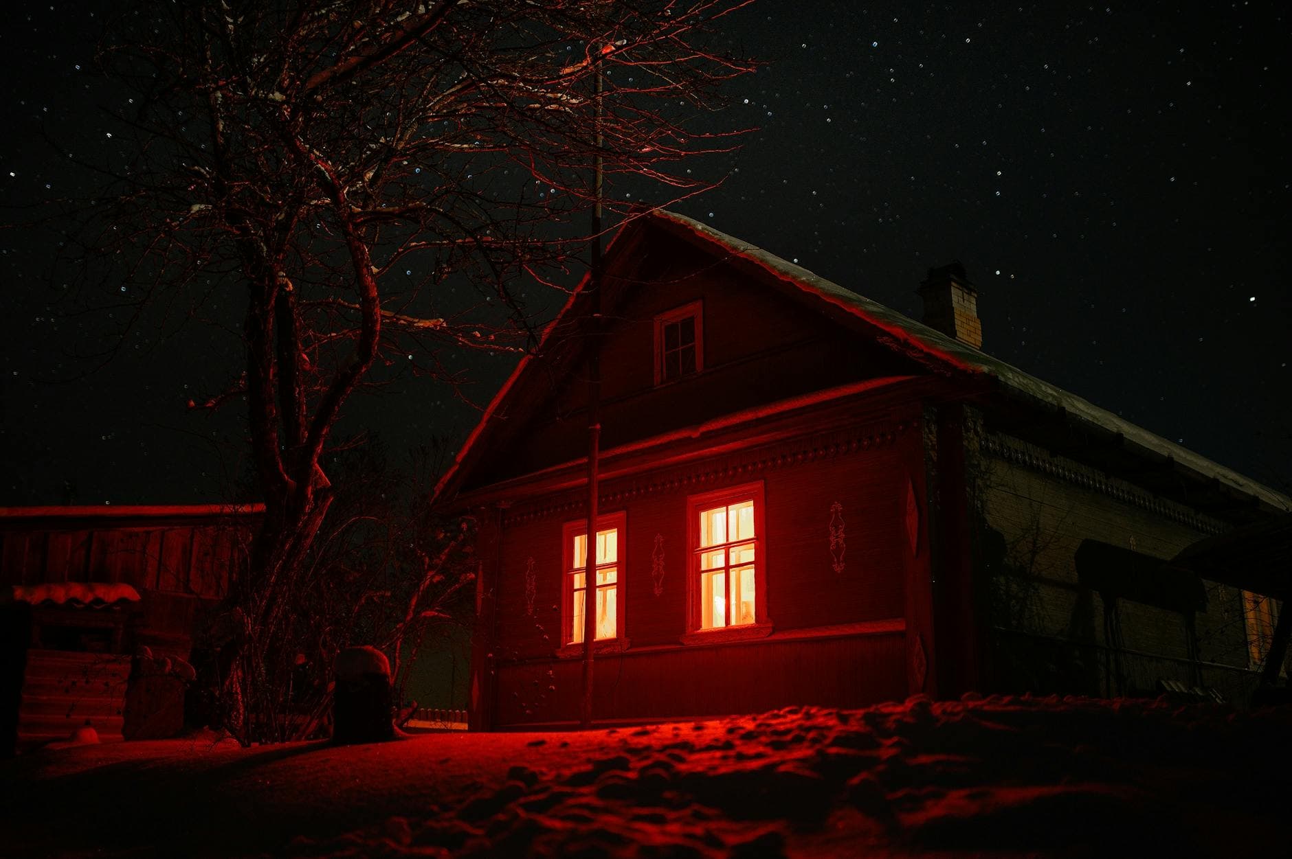 Eerie haunted house with red glowing windows under a starry night sky, perfect for spooky themes.