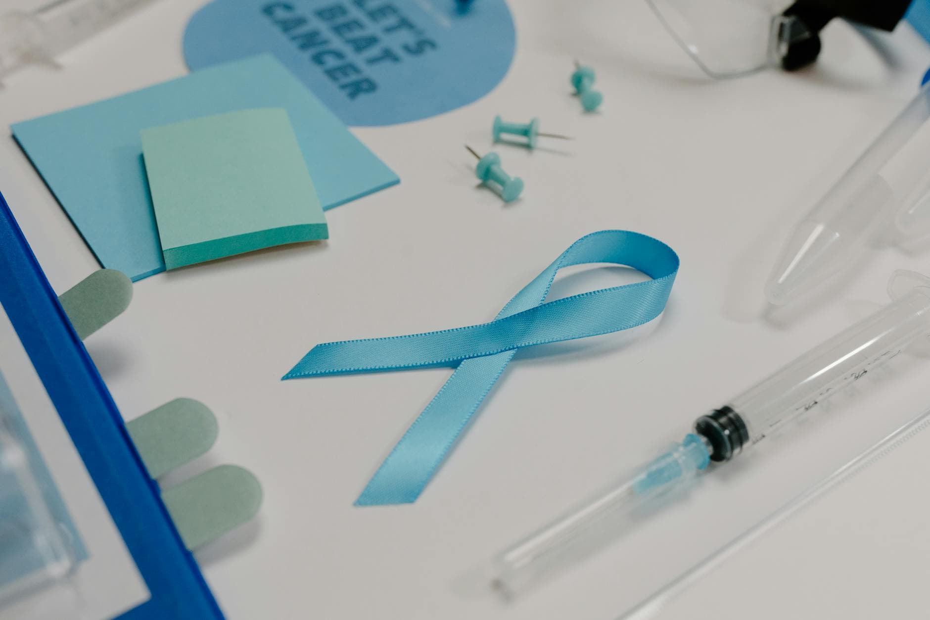 Blue ribbon with medical supplies symbolizes healthcare awareness and cancer support.