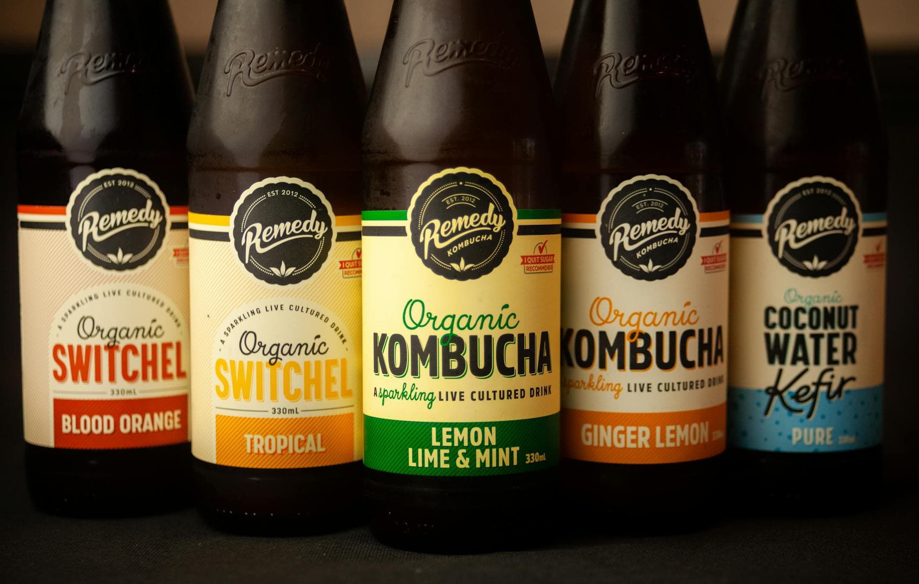 Close-up of five bottles featuring organic kombucha, switchel, and kefir with various flavors.