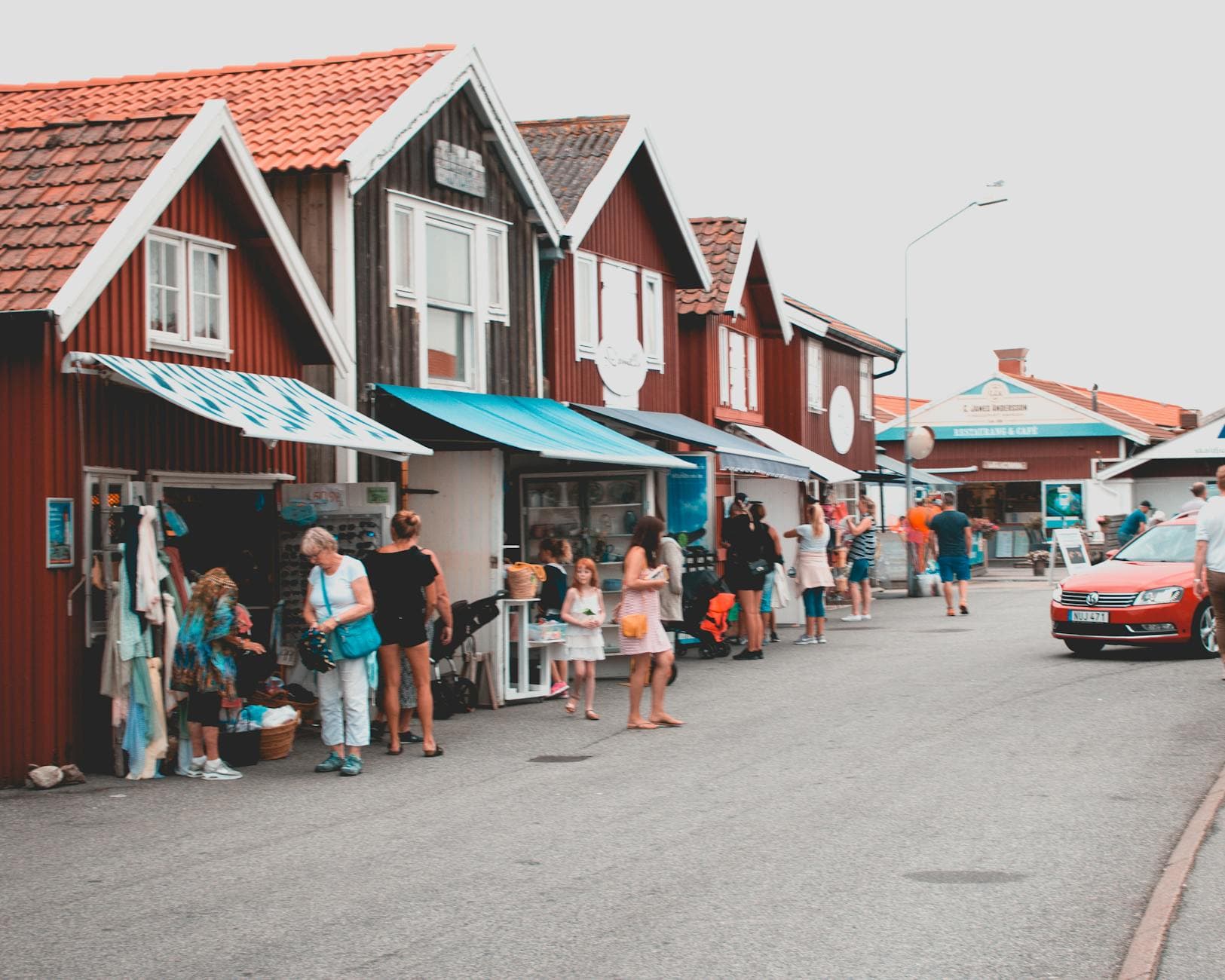 Bustling street in Smögen, Sweden with people shopping and colorful houses on a sunny day.