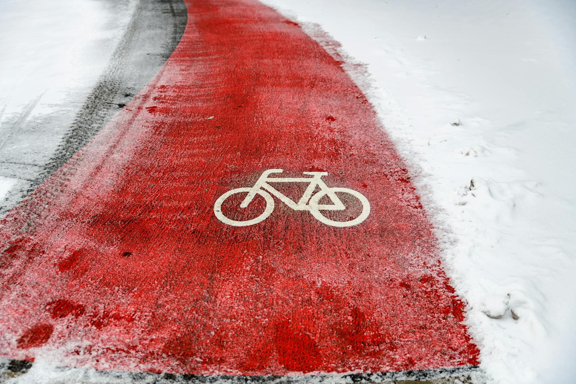 A red bike path stands out against the snowy landscape, featuring a bicycle symbol.
