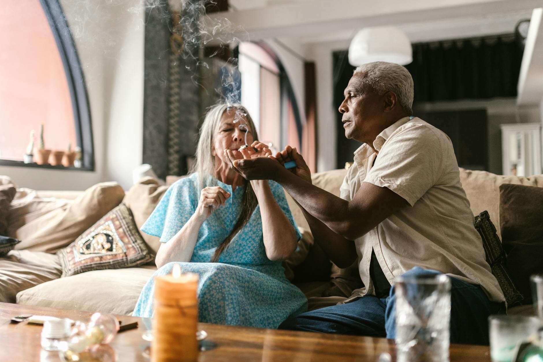 Elderly couple sharing a moment while using legal marijuana in a cozy living room.