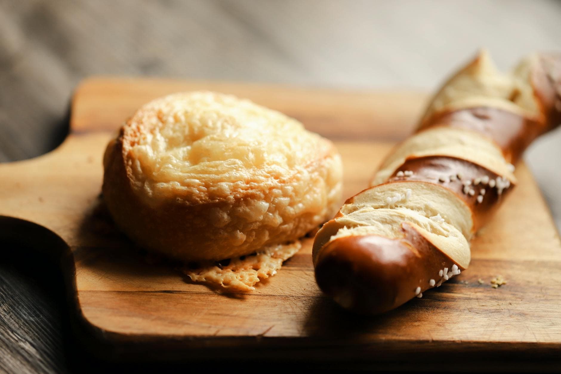 Gourmet cheese bread and pretzel on a wooden board. Perfect for bakery displays.